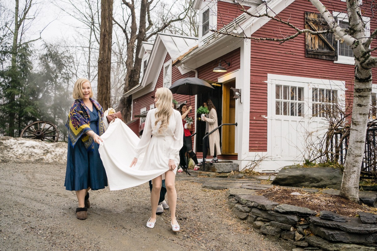 Bride and companion walking toward a red barn wedding venue entrance