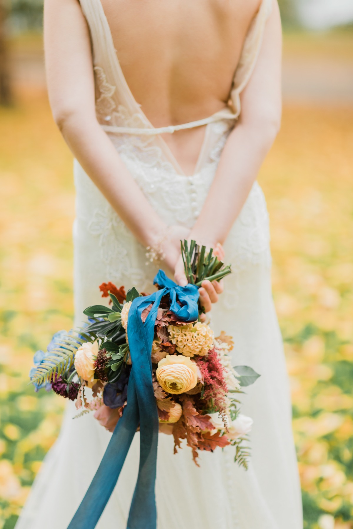 Bride holds vibrant wedding bouquet with blue ribbon