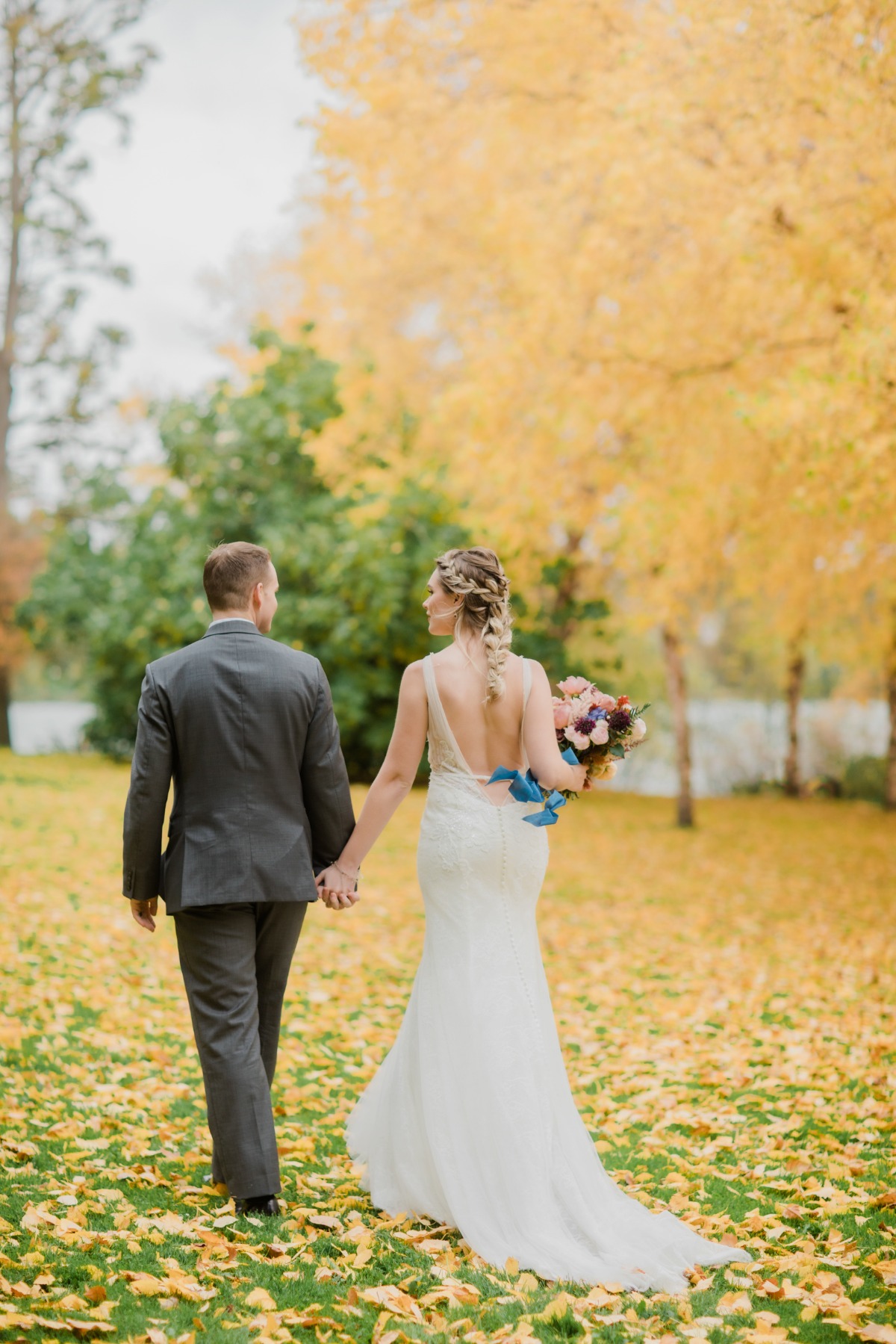 Newlyweds walk hand in hand through a fall foliage wedding scene