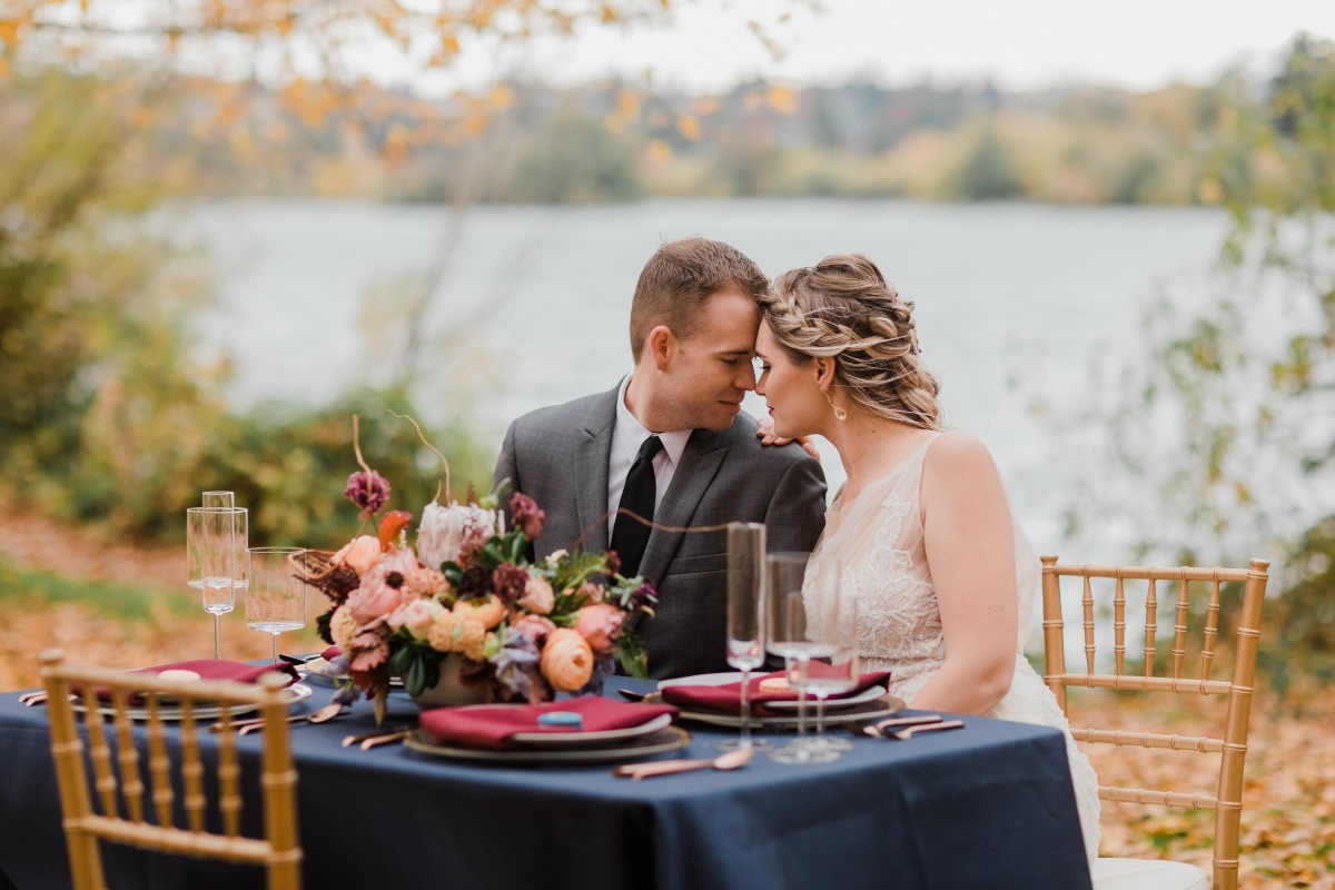 Bride and groom embrace at an outdoor wedding reception table