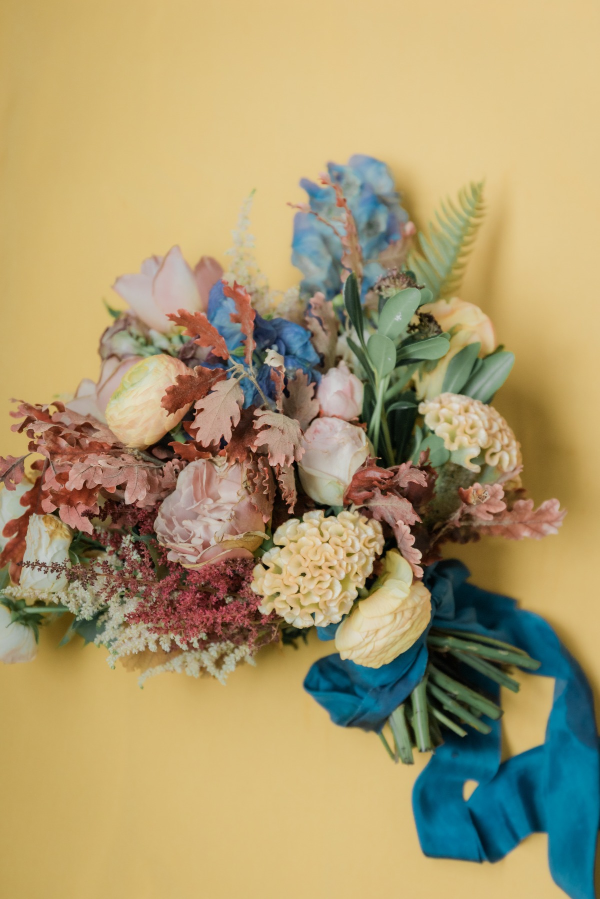 Colorful flower bouquet with a blue ribbon on yellow