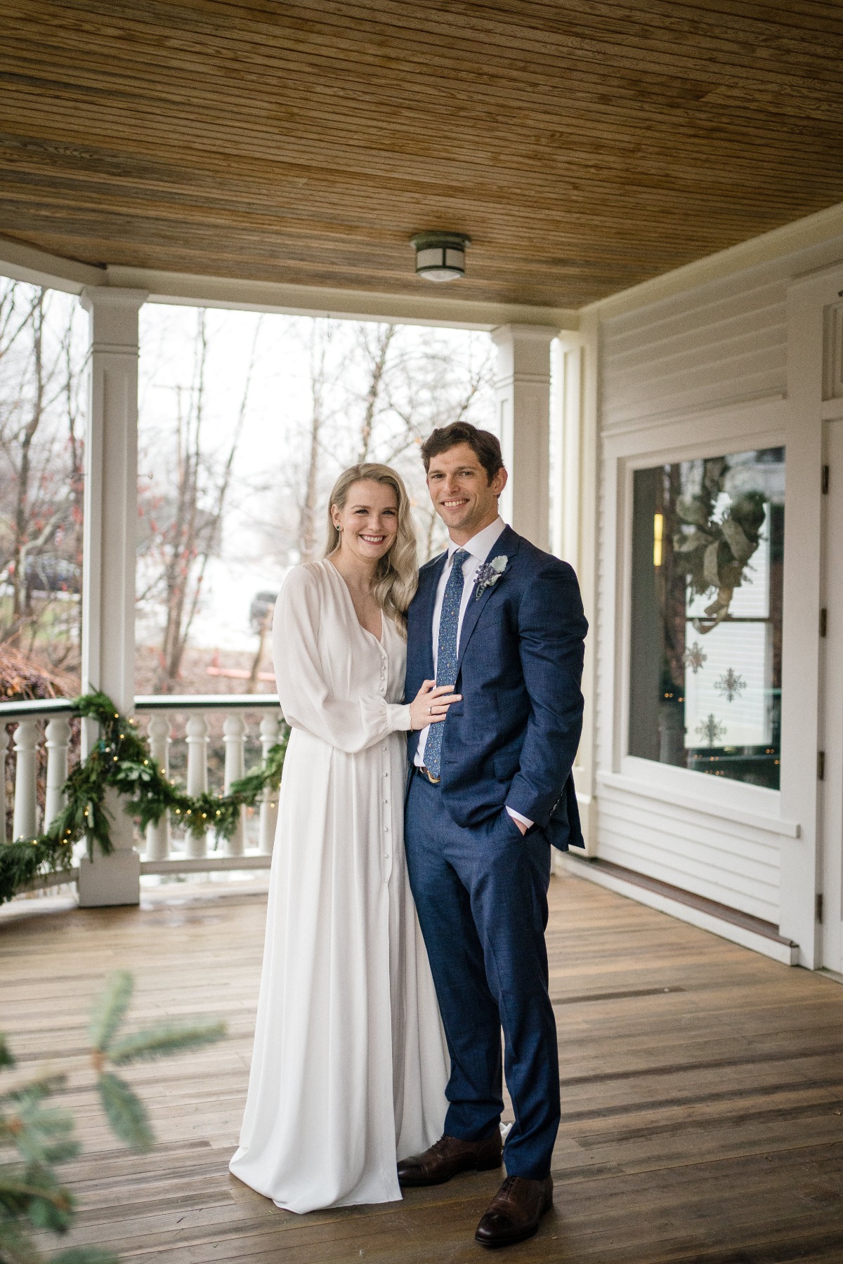 Newlyweds pose on a porch after their wedding ceremony