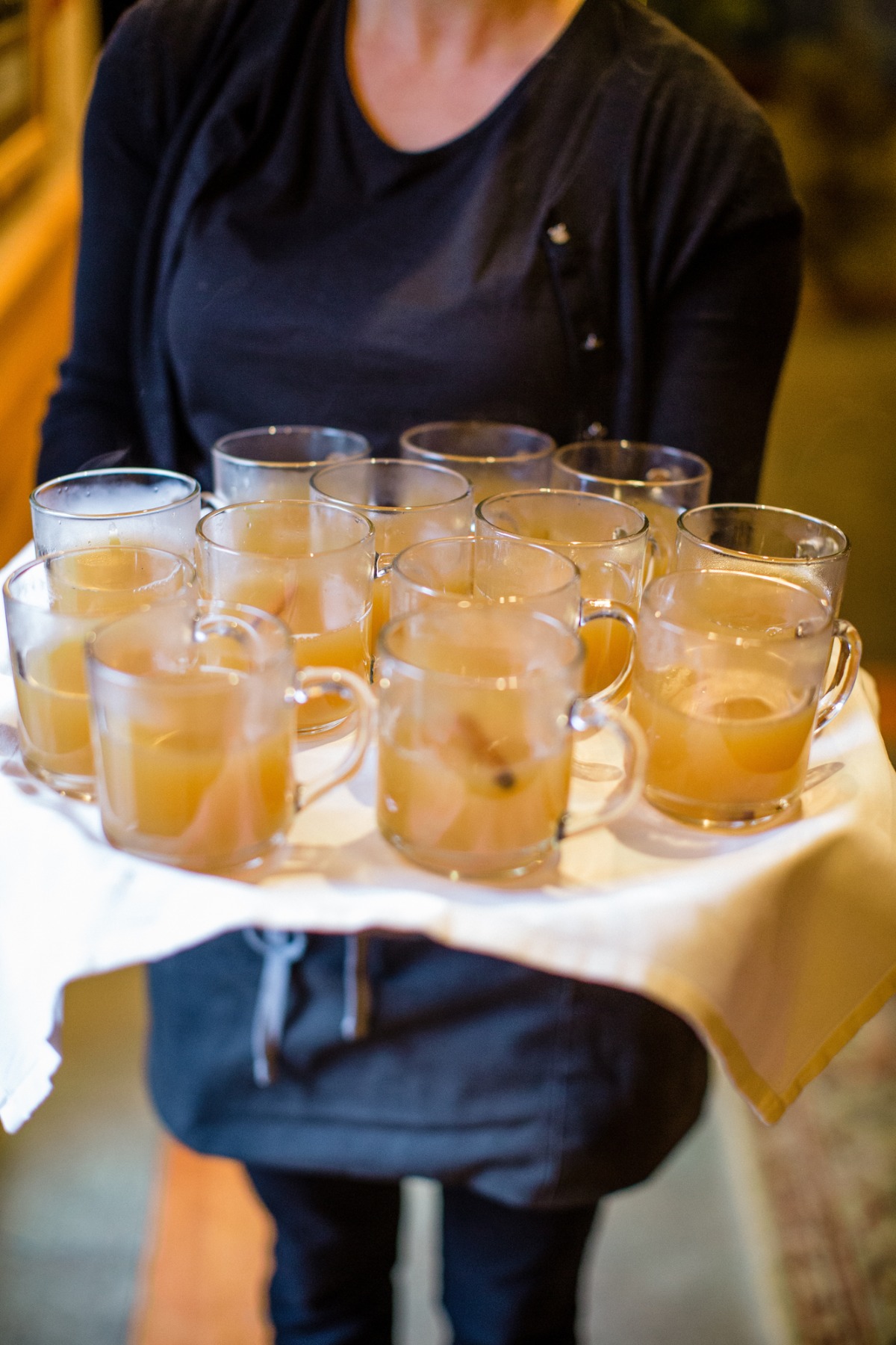 Server holding a tray of mugs filled with cider drinks
