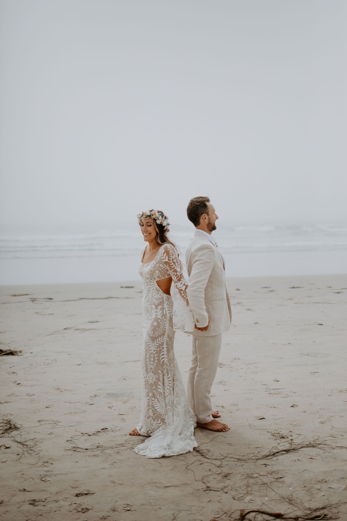 Bride and groom on a beach looking at the ocean during their wedding