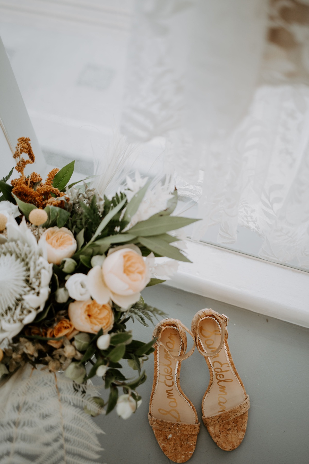 Elegant bridal shoes and floral bouquet on a bright surface