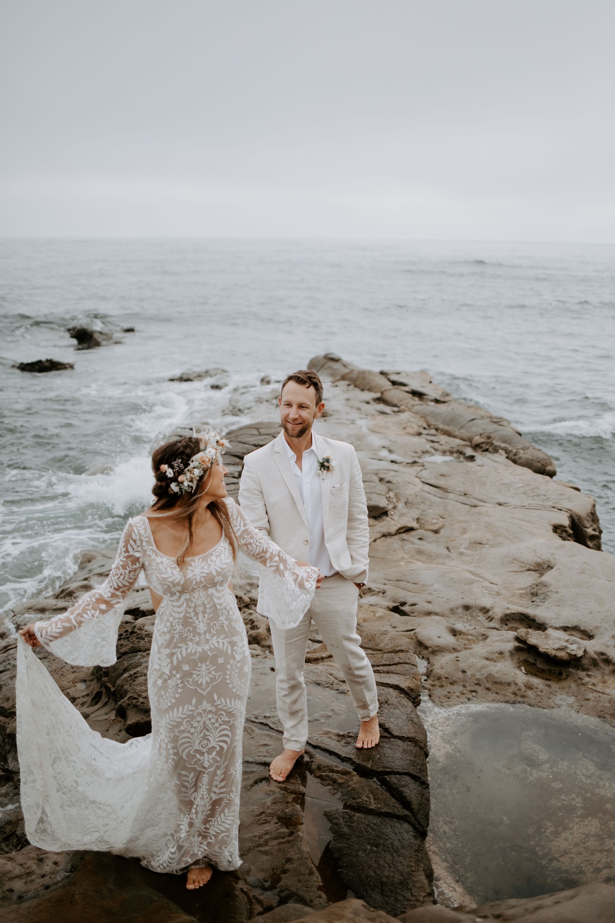 Bride and groom share loving moment on ocean rocks during wedding