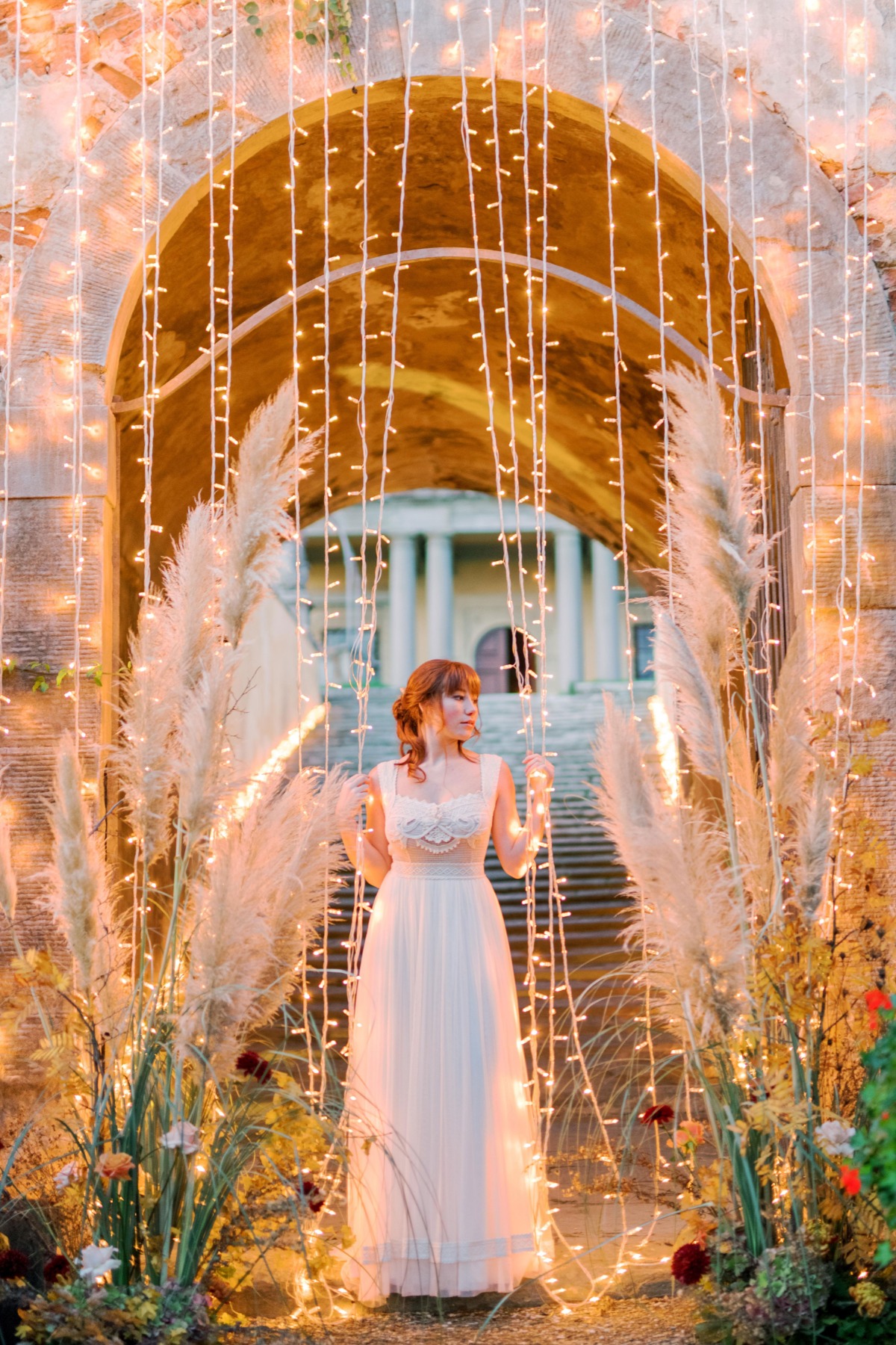 Bride in a fairy lit archway, elegant wedding photography scene