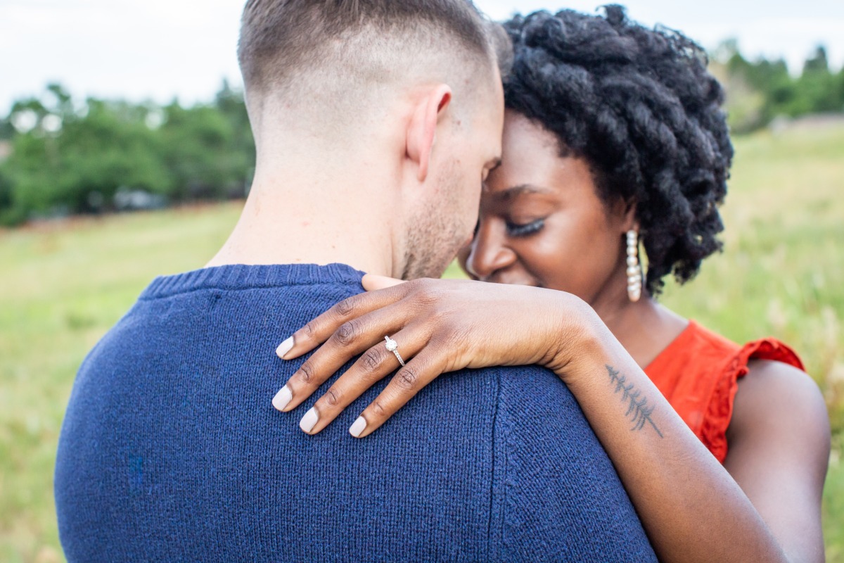 Engaged couple embracing outdoors, showcasing engagement ring