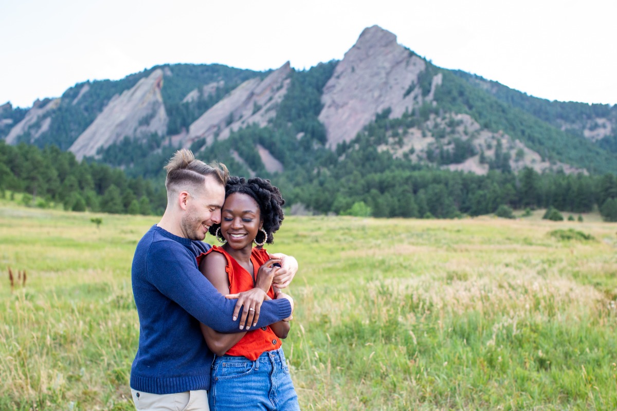 Happy couple embracing in scenic mountain field