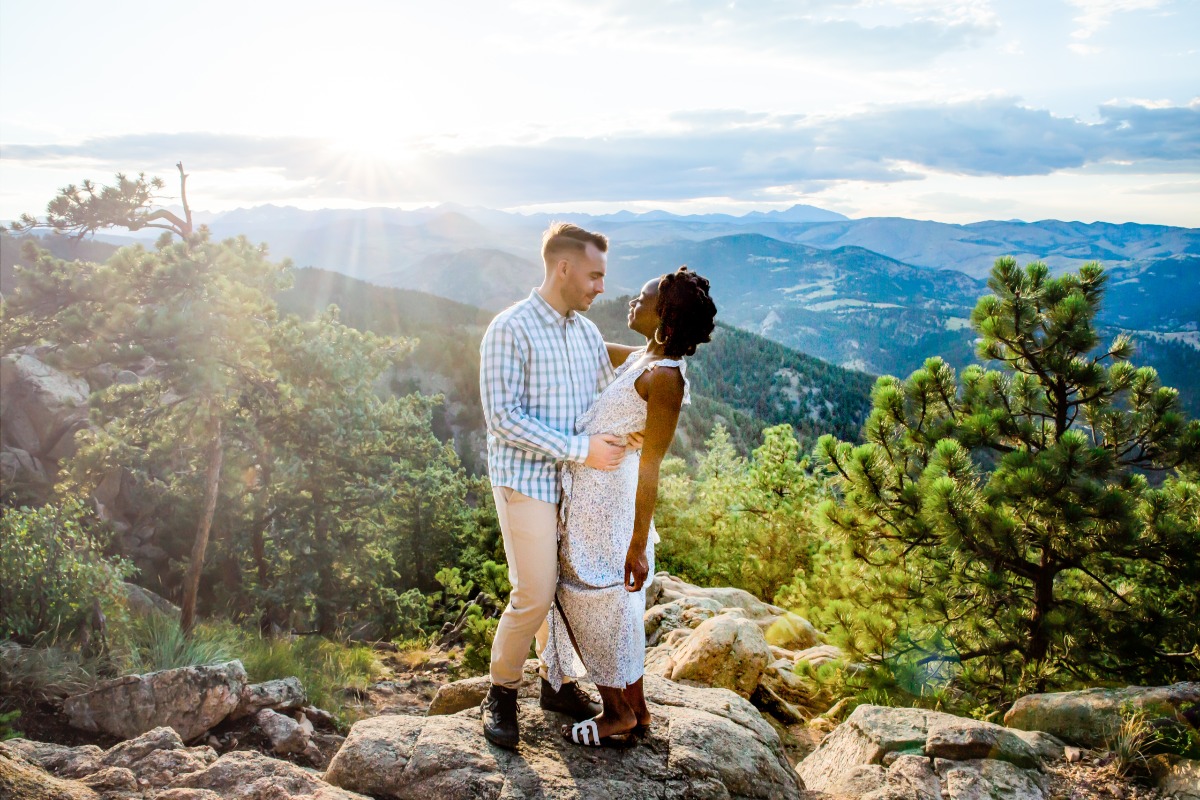 Romantic couple embraces atop mountain, scenic view