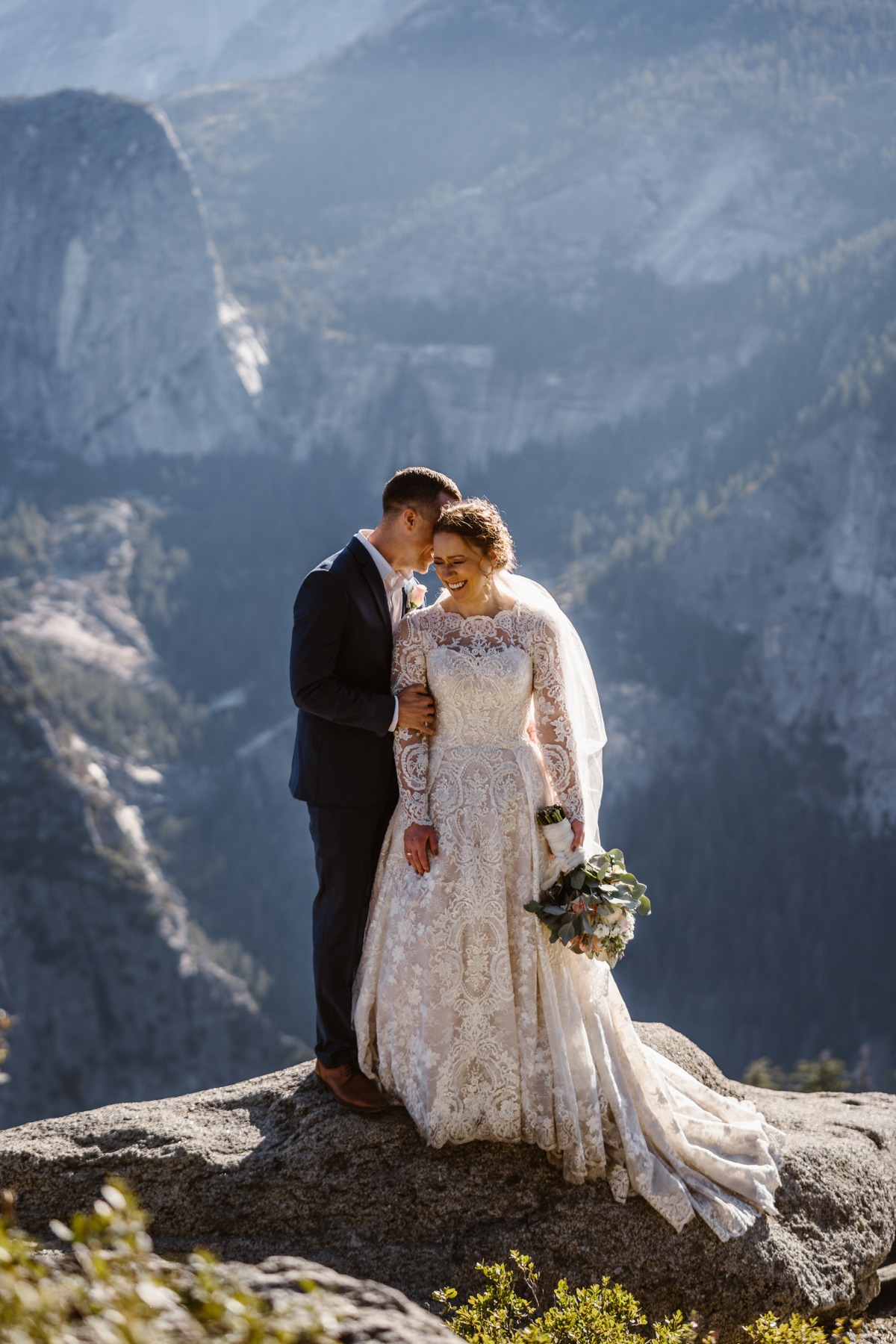 Bride and groom embracing on scenic mountain viewpoint