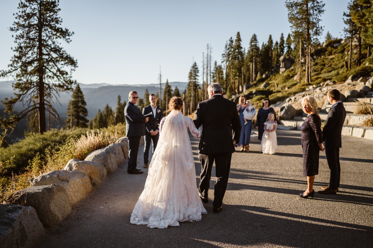 Bride walks down outdoor aisle with father at mountain wedding