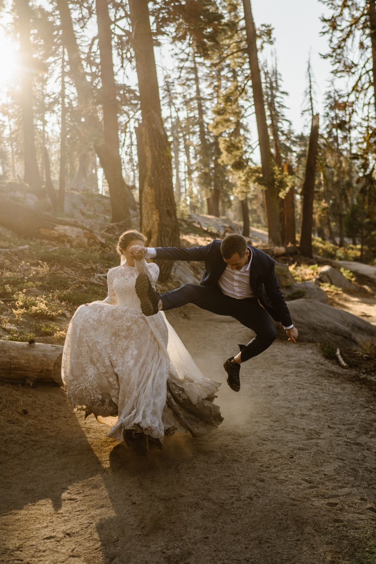 Joyful groom leaps over forest log beside his bride