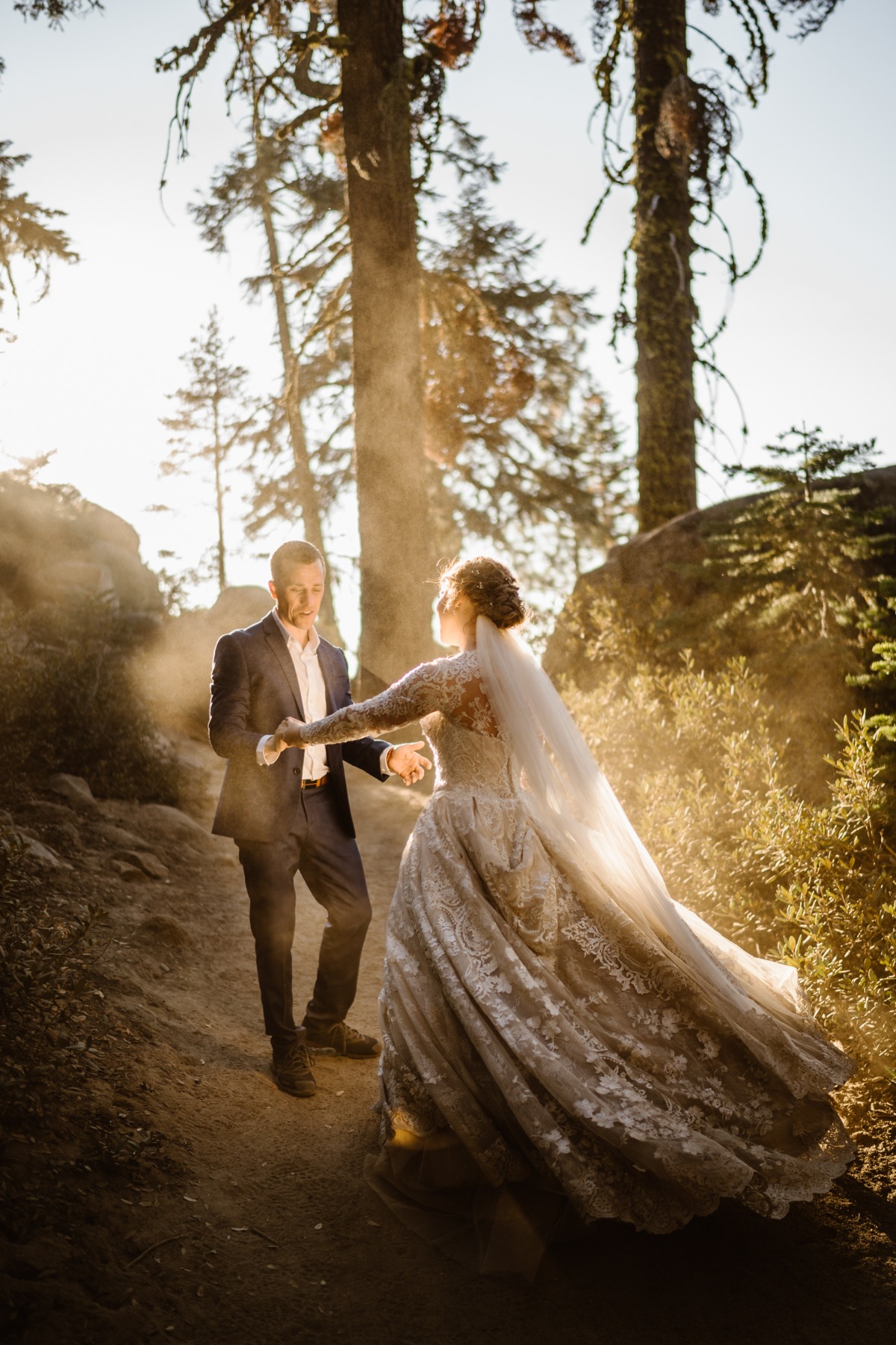 Newlyweds dance romantically in sunlit forest path