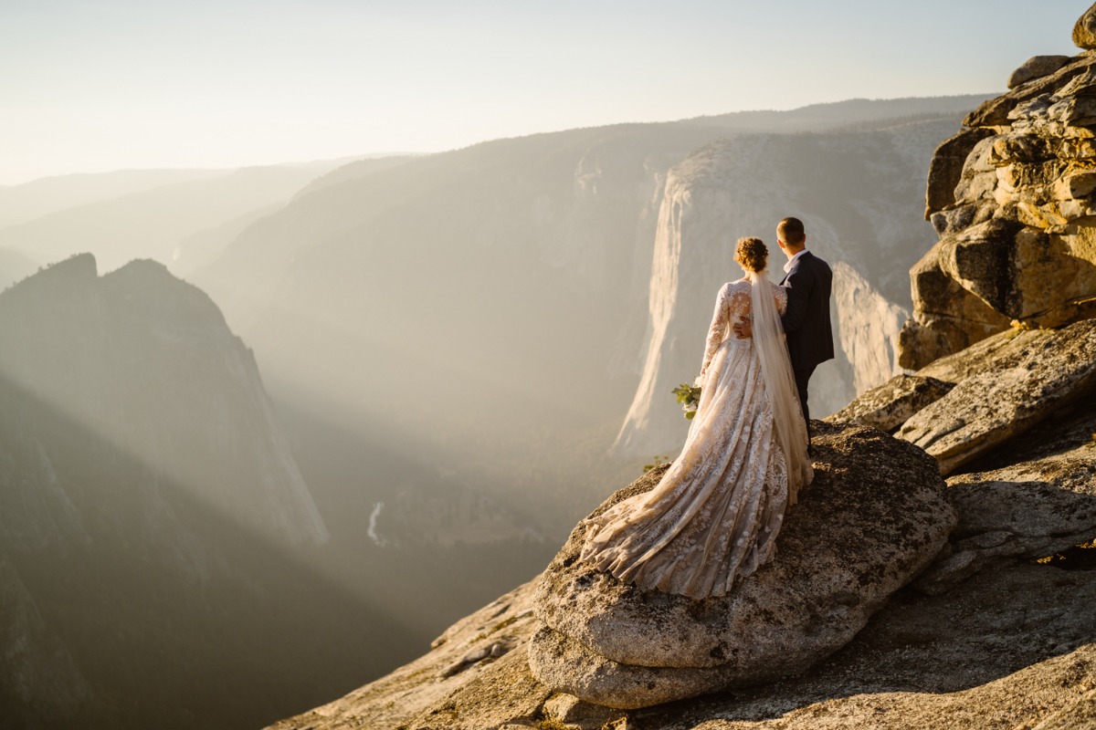 Bride and groom gaze at epic mountain view at sunrise
