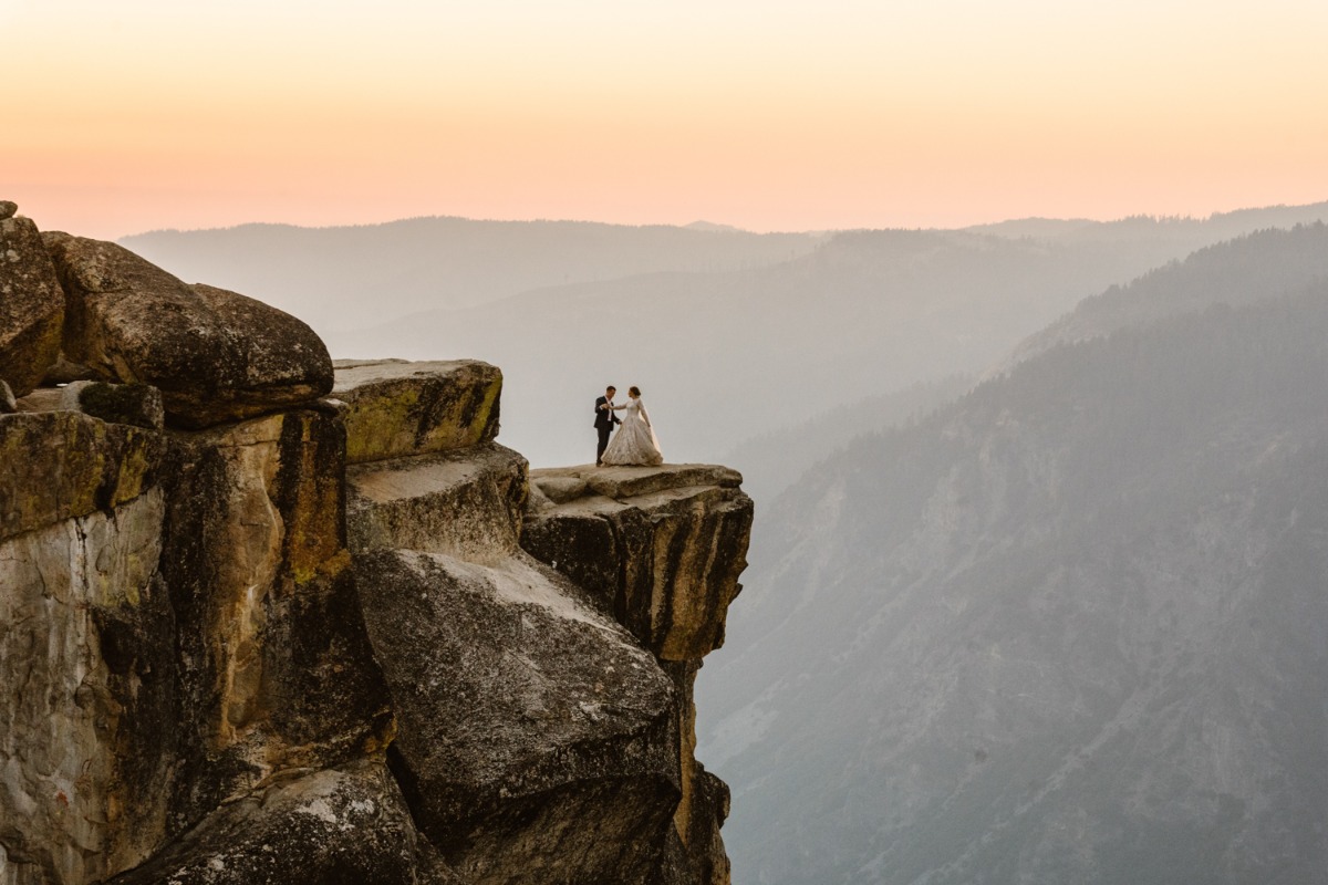 Epic wedding photo of couple on a cliff at sunset