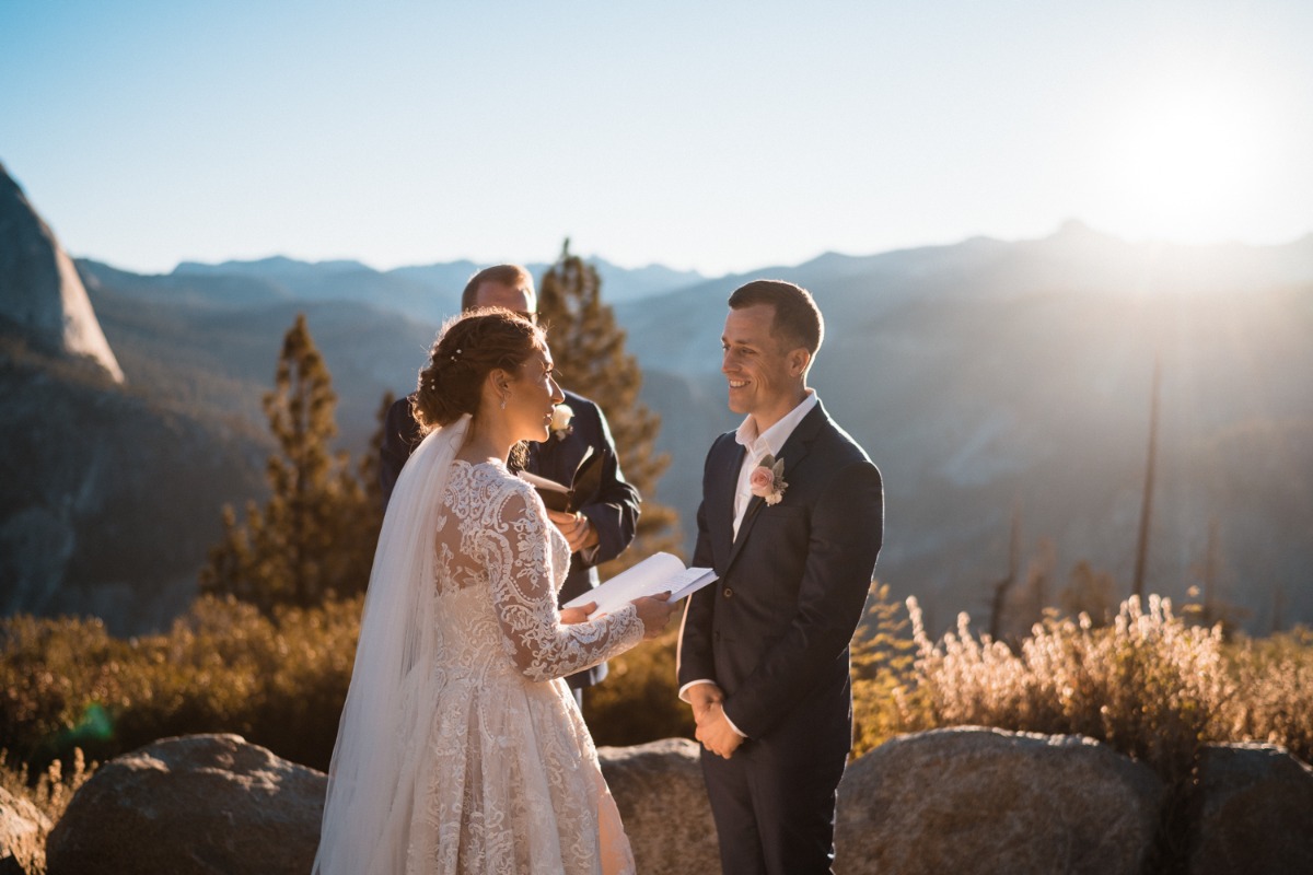 Bride reads vows to smiling groom at outdoor mountain wedding