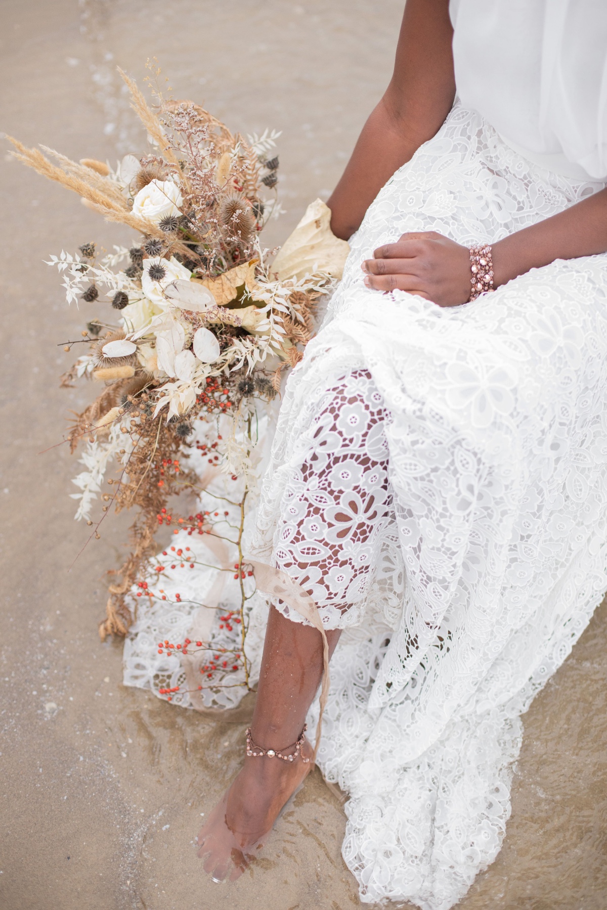 Beach bride with floral bouquet and delicate lace dress