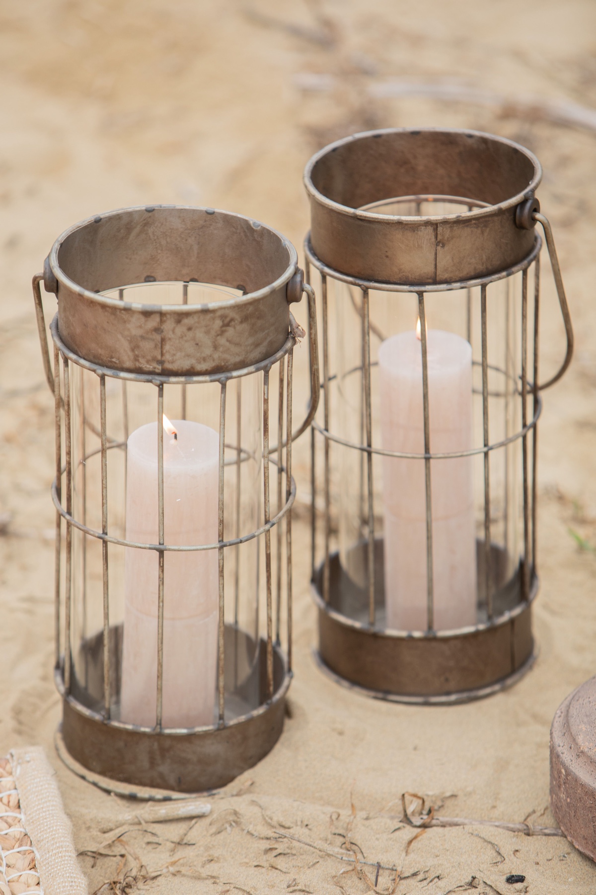 Two rustic metal candle lanterns with candles inside