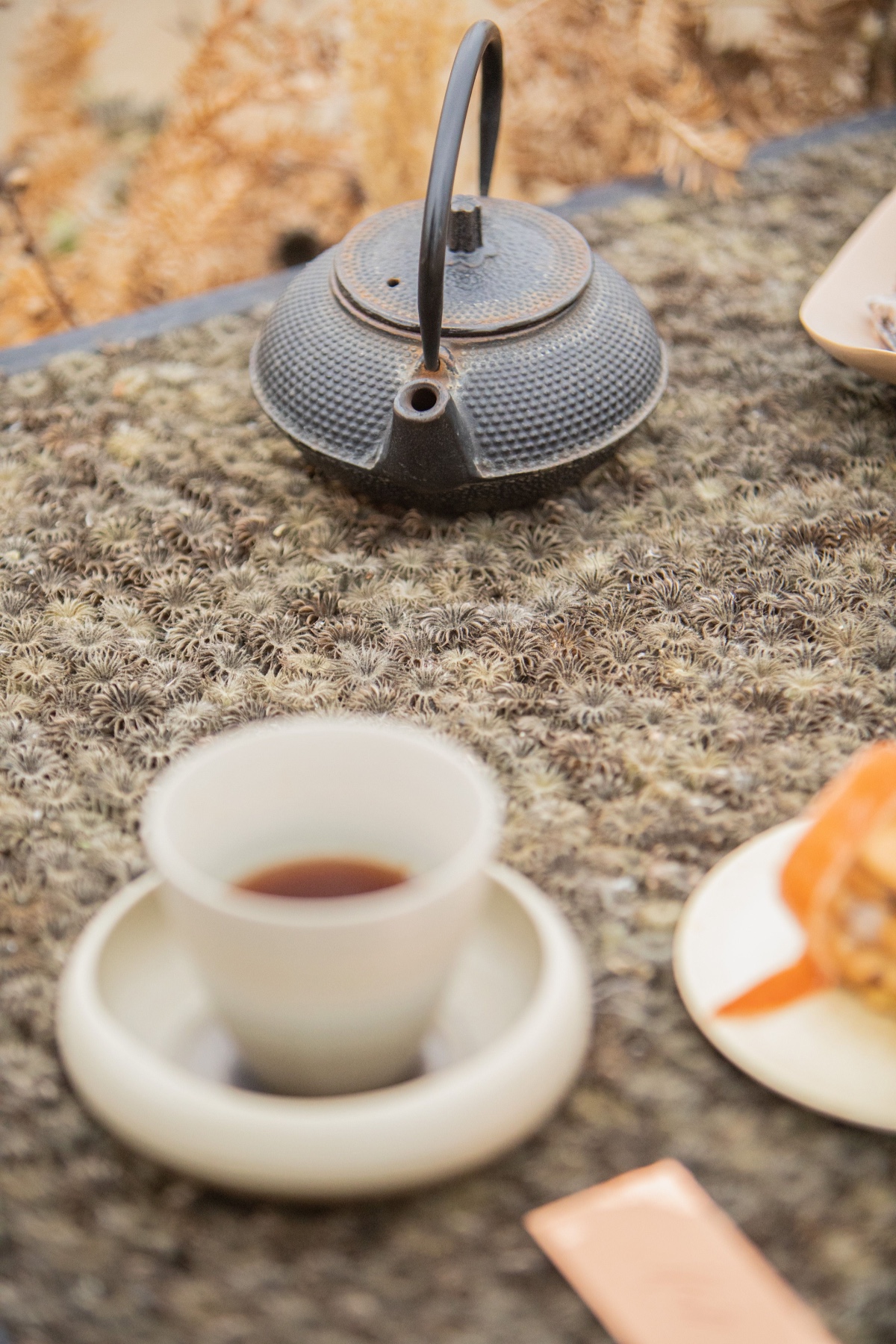Black cast iron teapot with a cup of tea and dessert