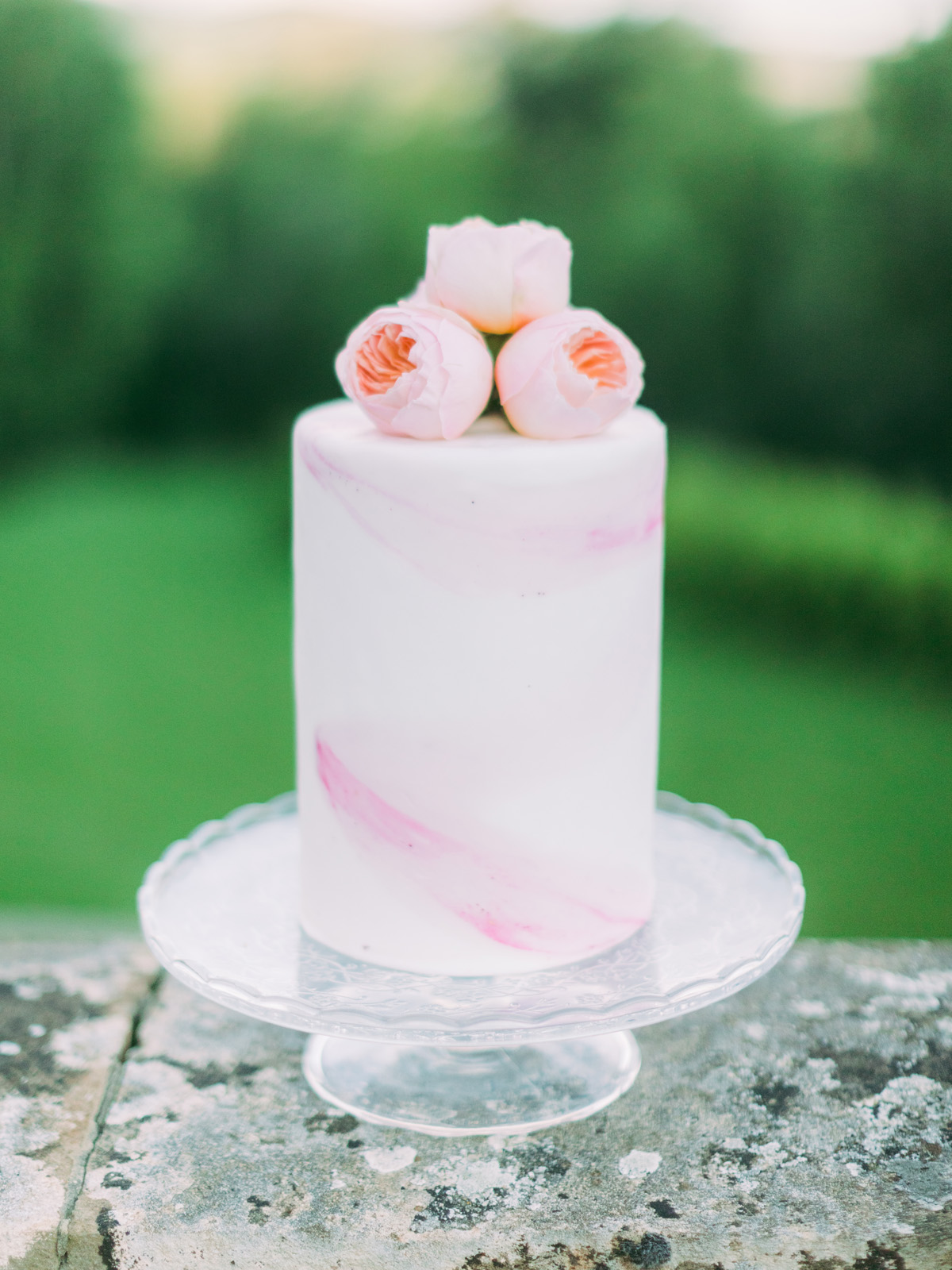 Elegant white cake with pink swirls and floral topper