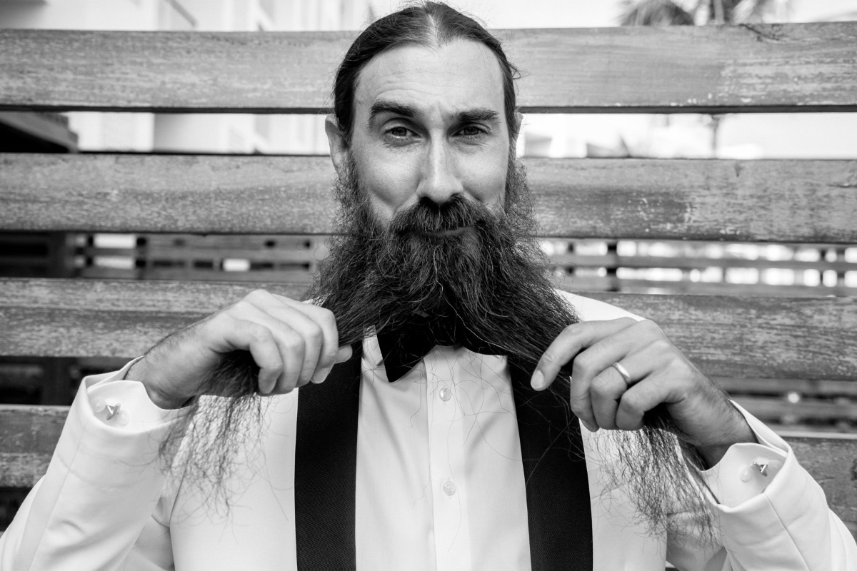 Black and white image of man styling his long beard