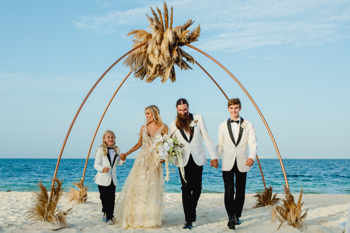 Joyful family walk on beach after beautiful wedding