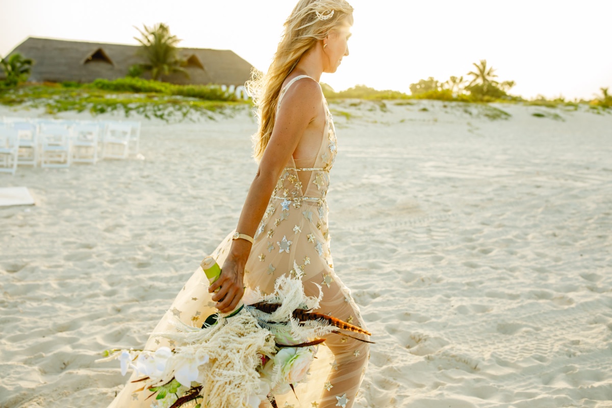Elegant bride in starry dress walks on sandy beach