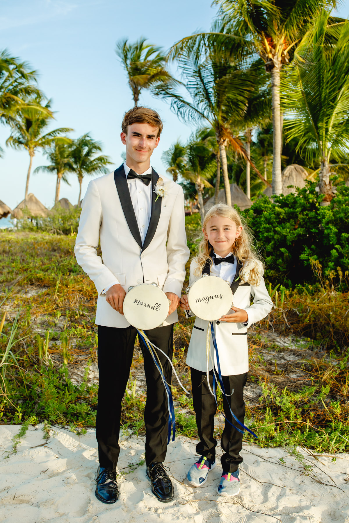 Smiling man and boy in tuxedos with tambourines on beach