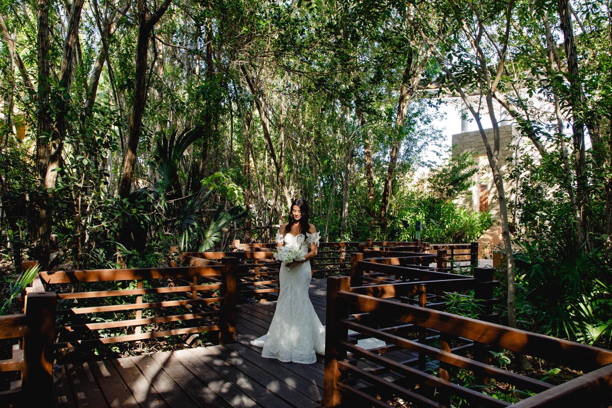 Bride poses with bouquet on jungle boardwalk wedding