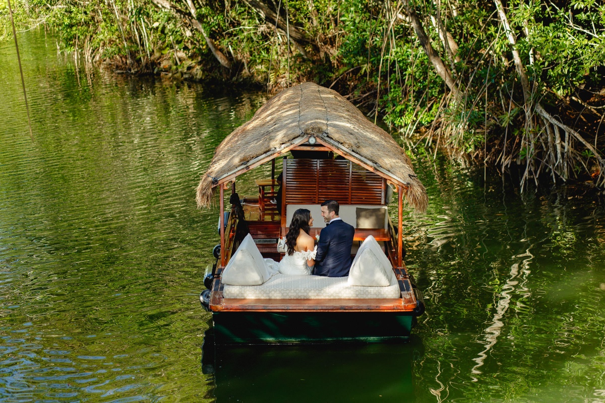 Newlyweds on a thatched boat ride at jungle resort