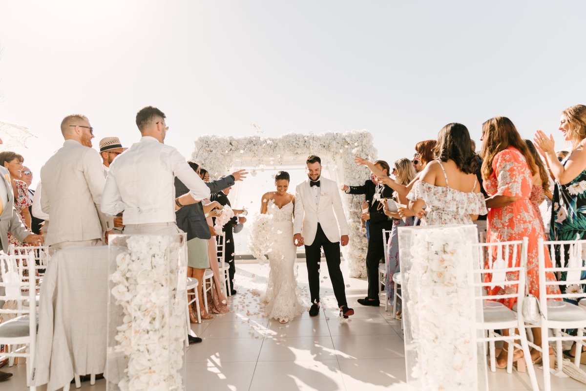 Bride and groom exit wedding ceremony, showered with petals