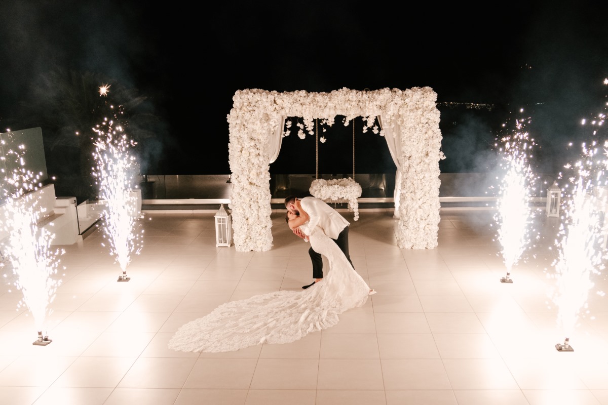 Couple kissing at wedding with fireworks and floral archway