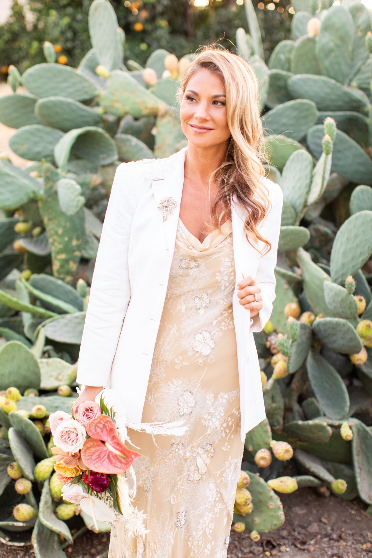Elegant bride with floral bouquet in front of cactus plants