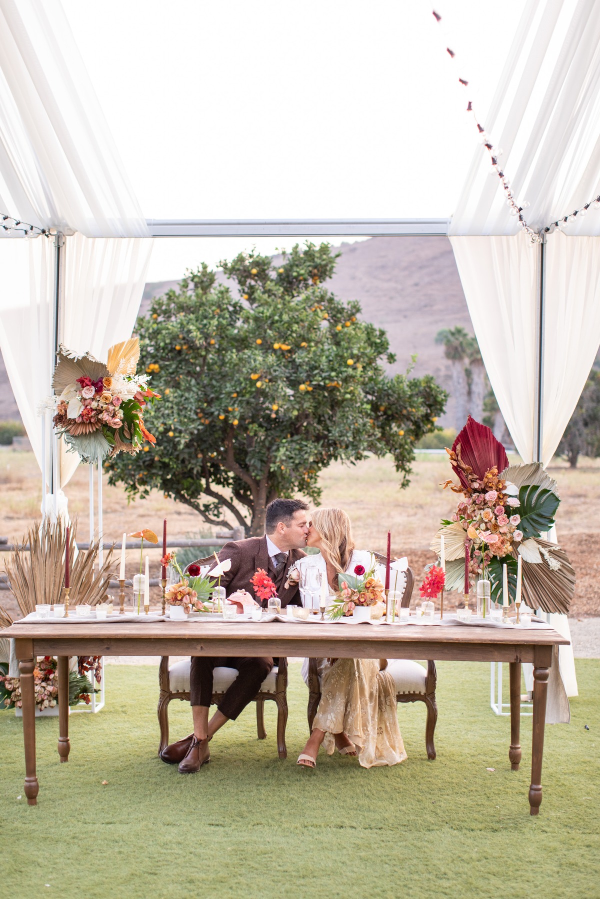 Newlyweds share a kiss at their outdoor wedding table