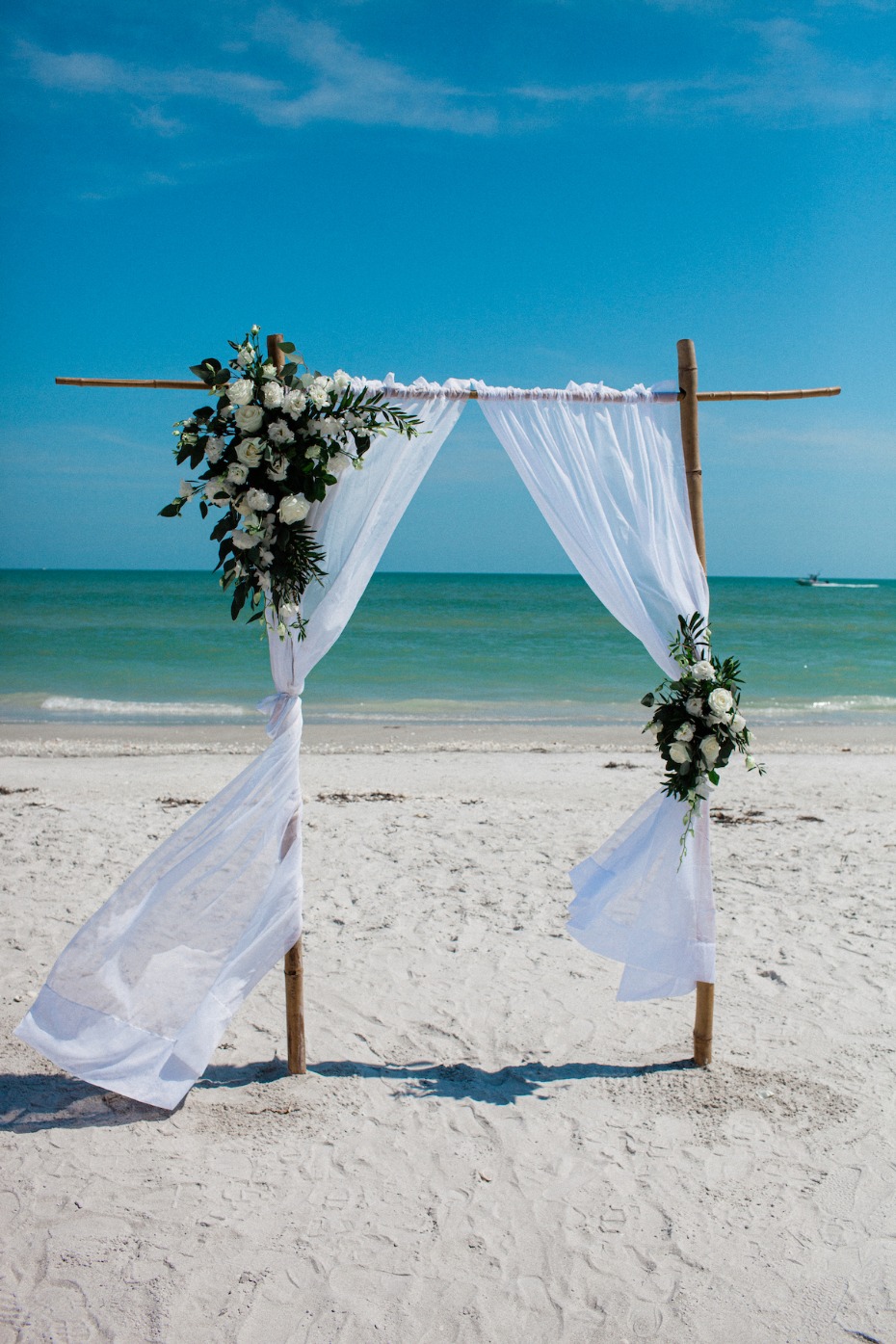 Beach wedding arch with flowers and flowing white fabric