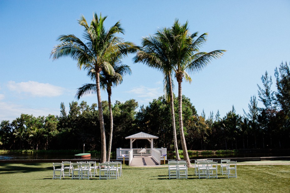 Wedding ceremony setup with palm trees and gazebo by the lake
