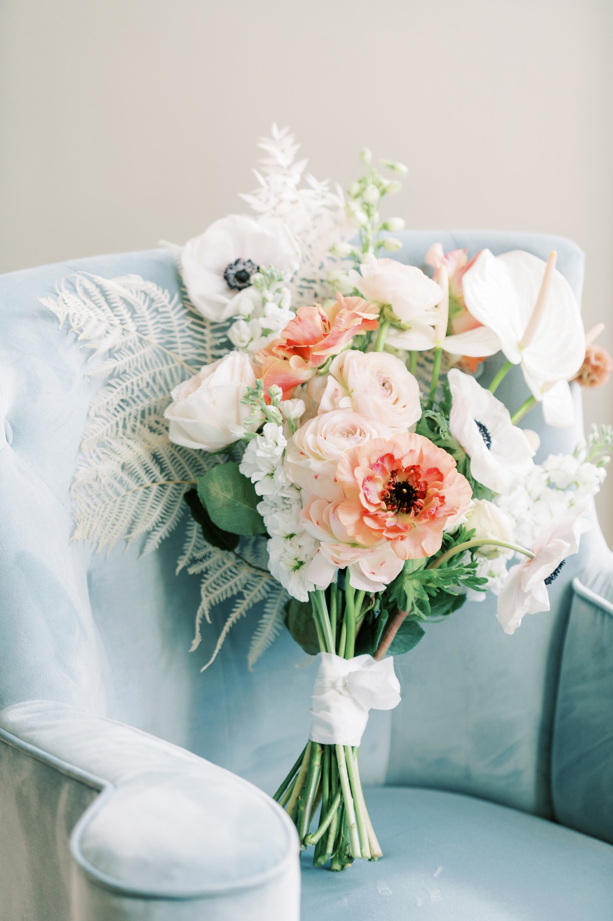 Elegant wedding bouquet on a plush blue velvet chair