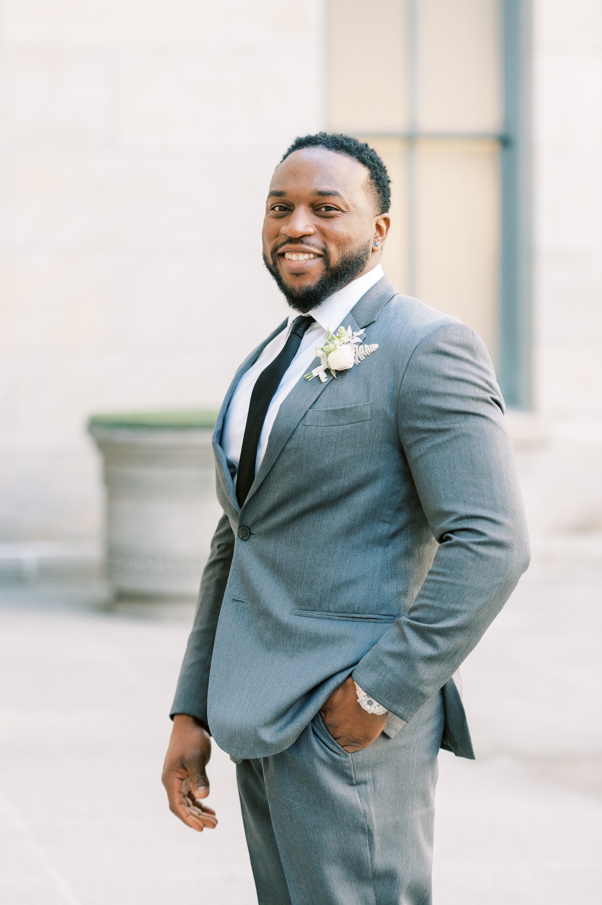 Smiling groom in a stylish gray suit with boutonniere