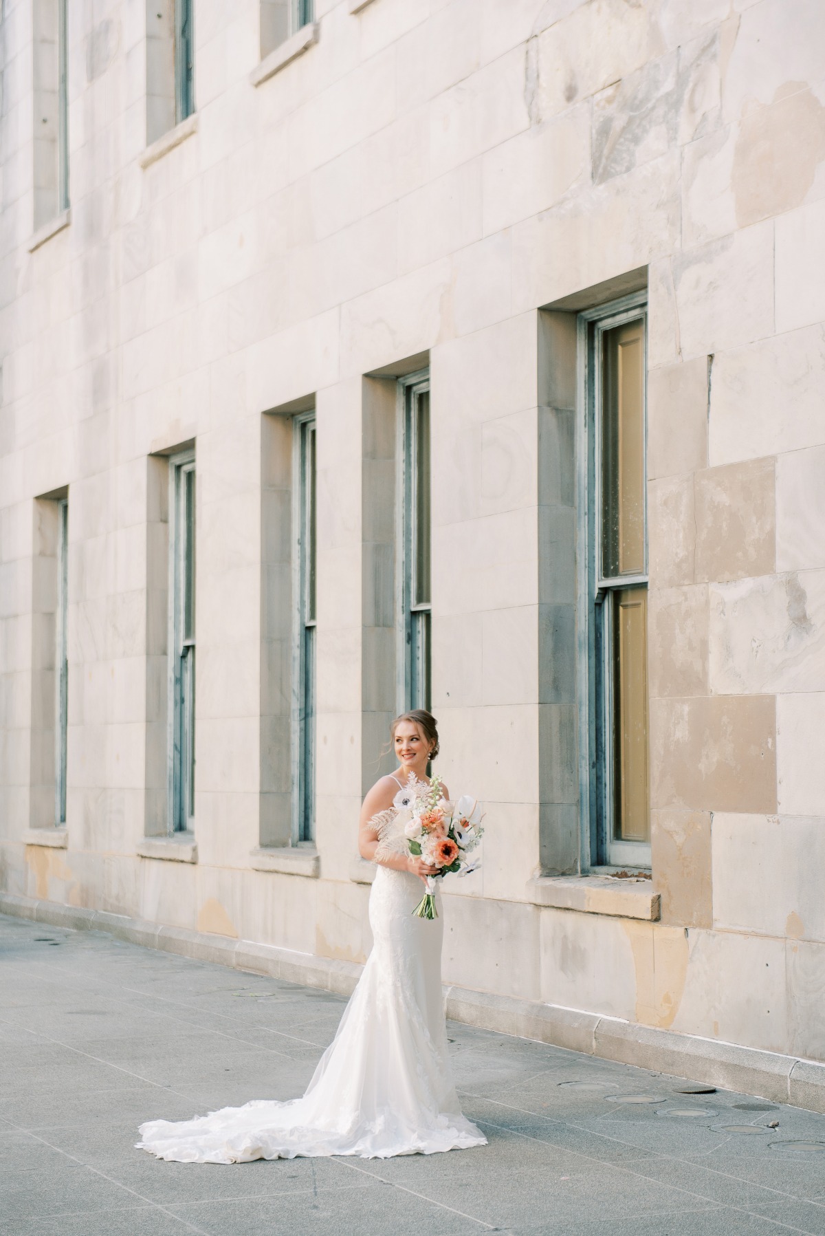 Elegant bride with bouquet posing by stone building