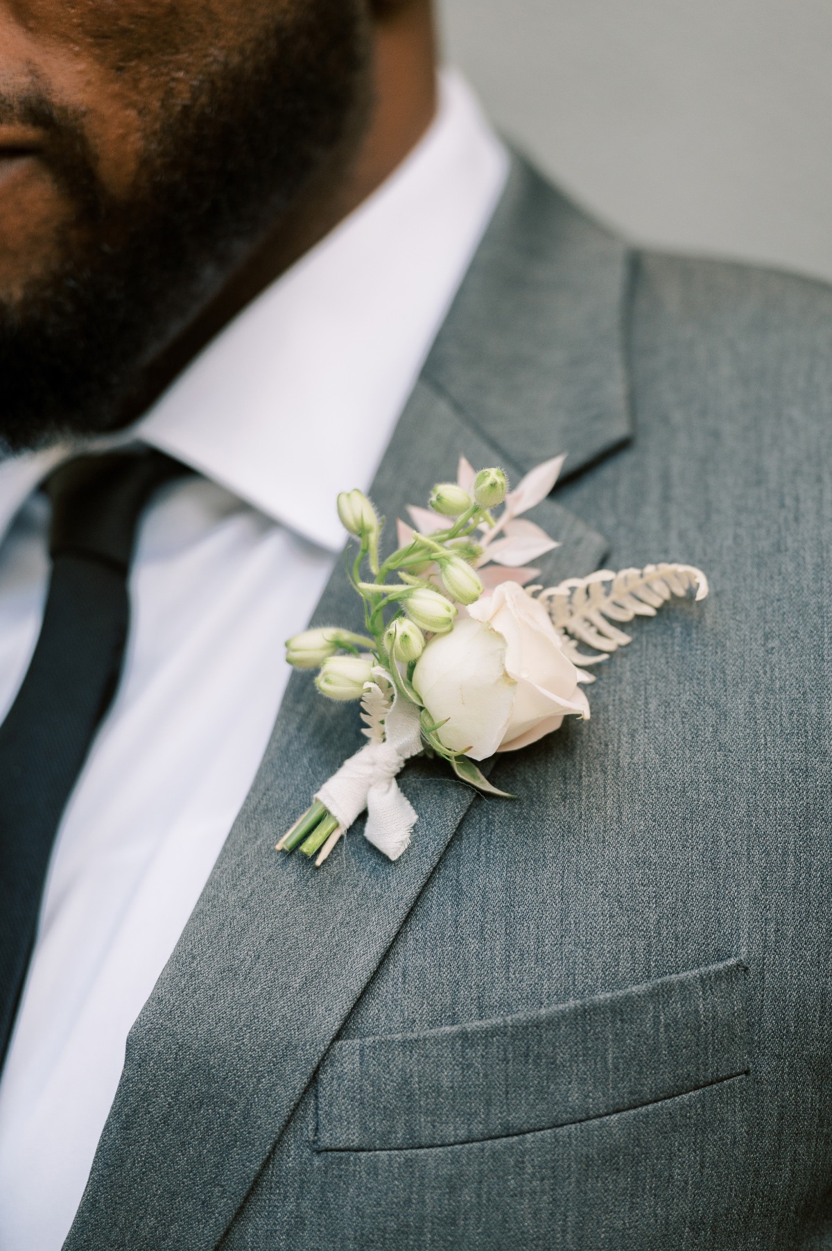Groom in gray suit with a boutonniere flower detail