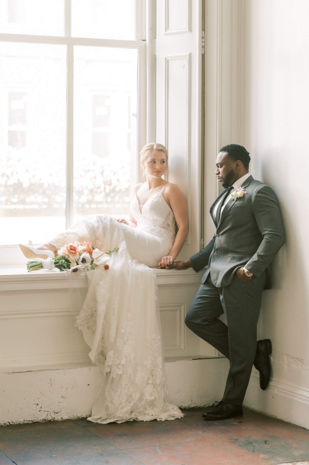 Elegant bride and groom pose in window light for wedding day