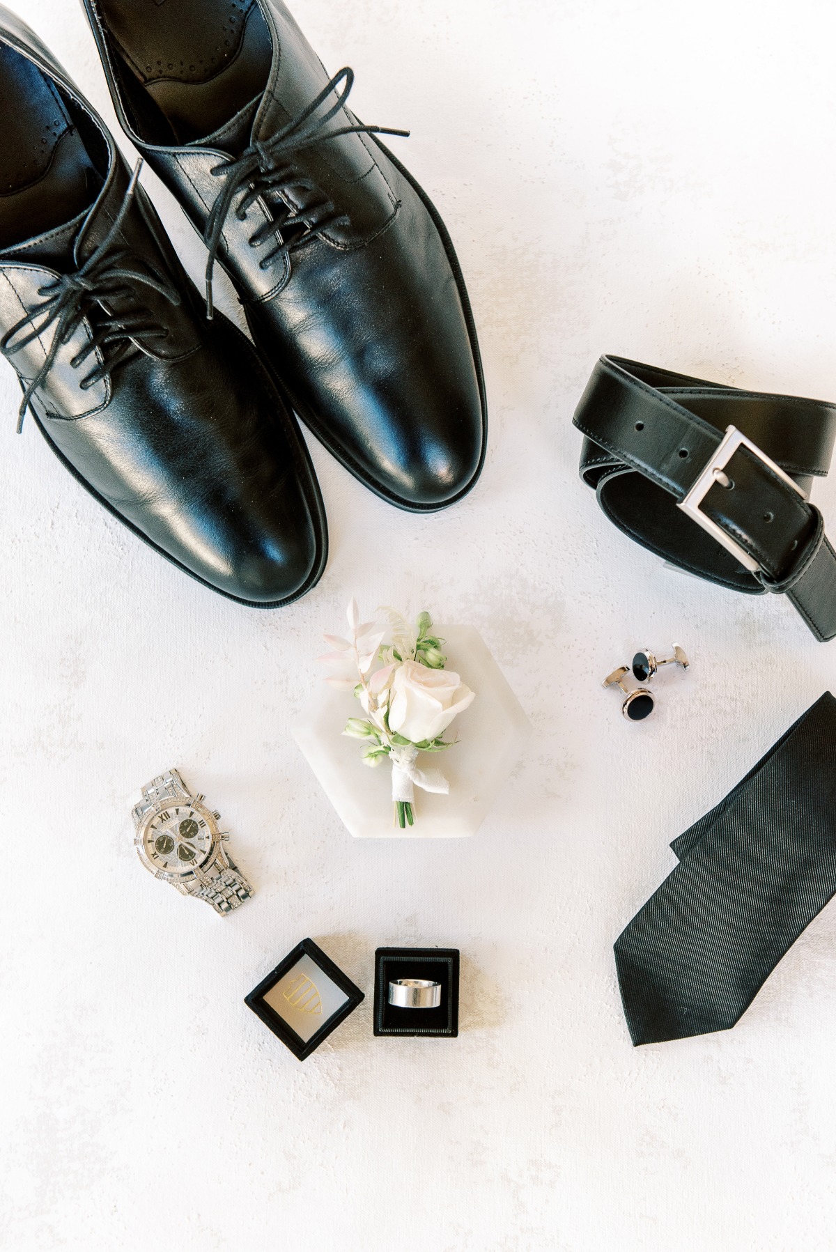 Grooms black leather shoes, tie, belt, boutonniere and ring