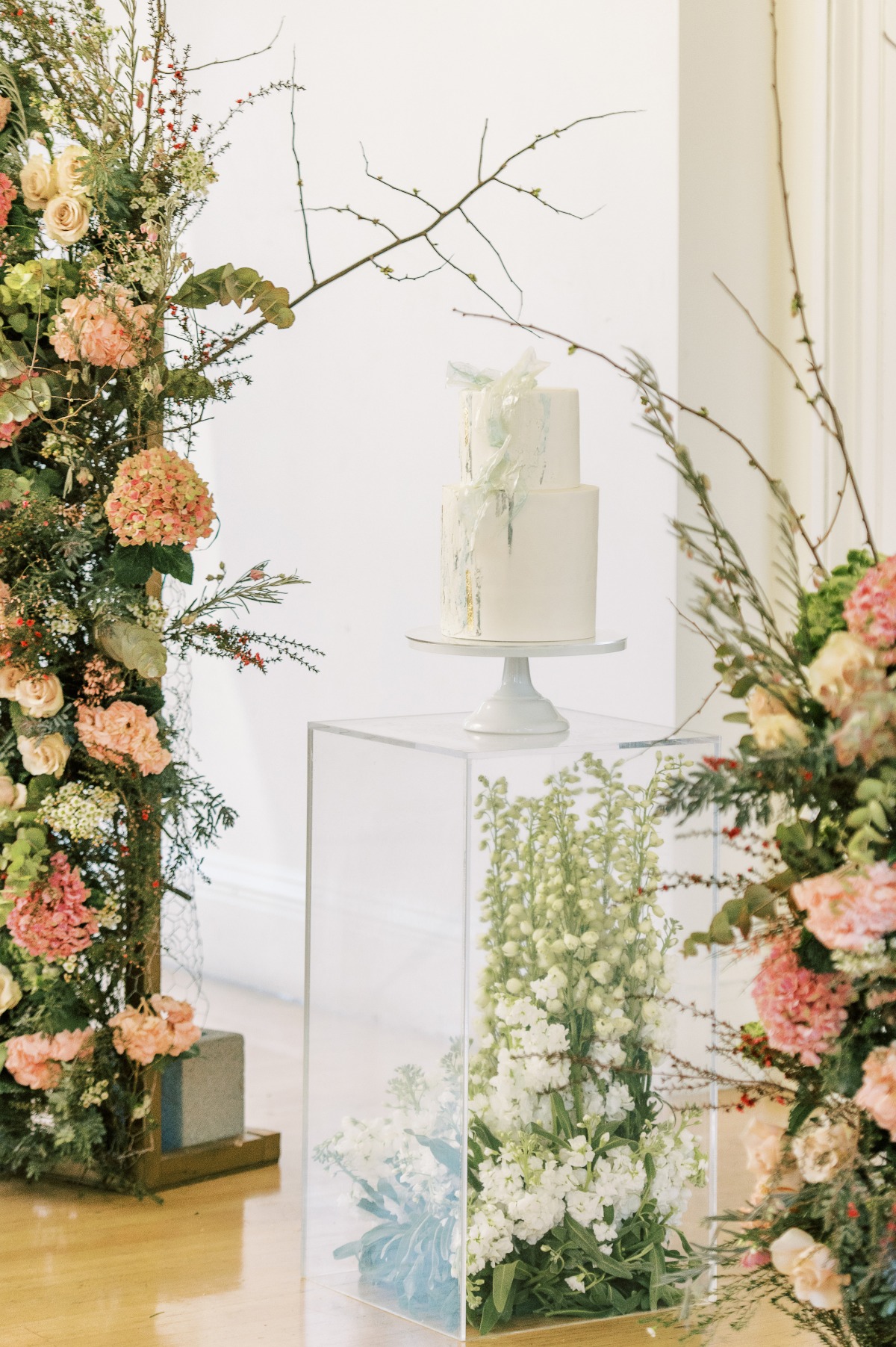 Elegant white wedding cake on floral pedestal display