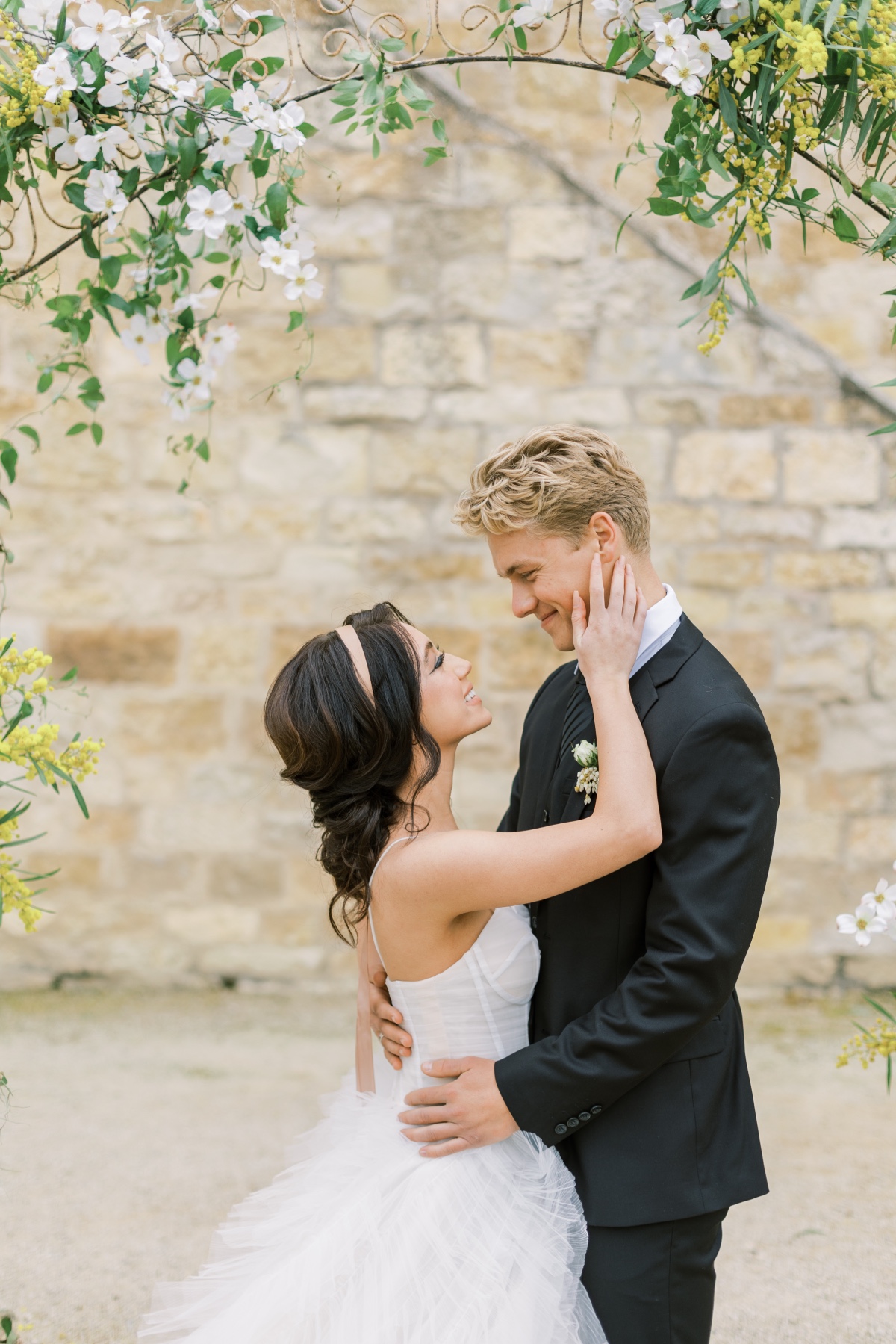 Romantic wedding couple embracing under floral arch