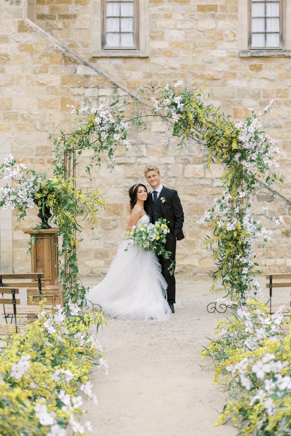 Happy couple posing for wedding photo under floral arch