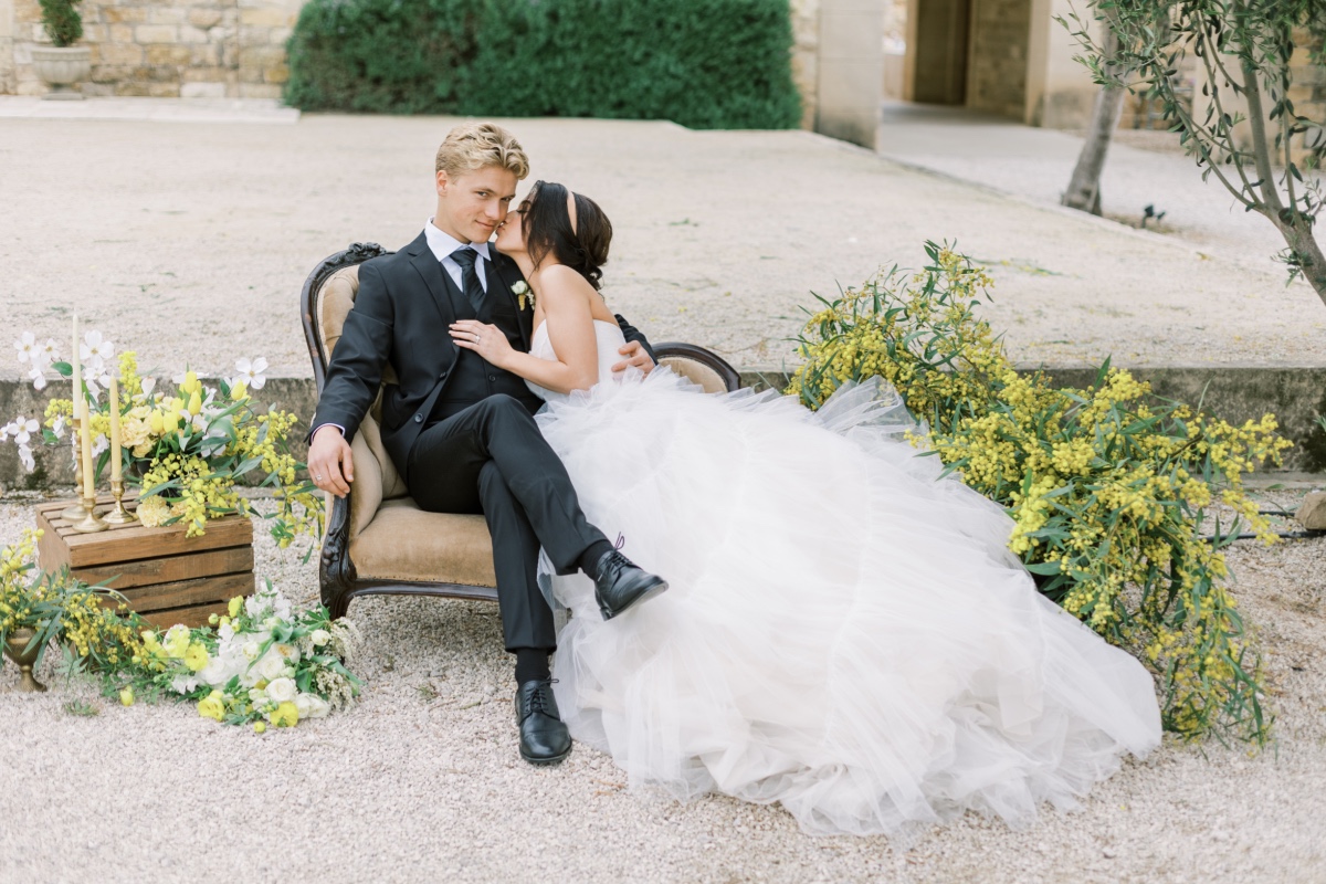 Bride kisses groom on cheek in outdoor wedding portrait