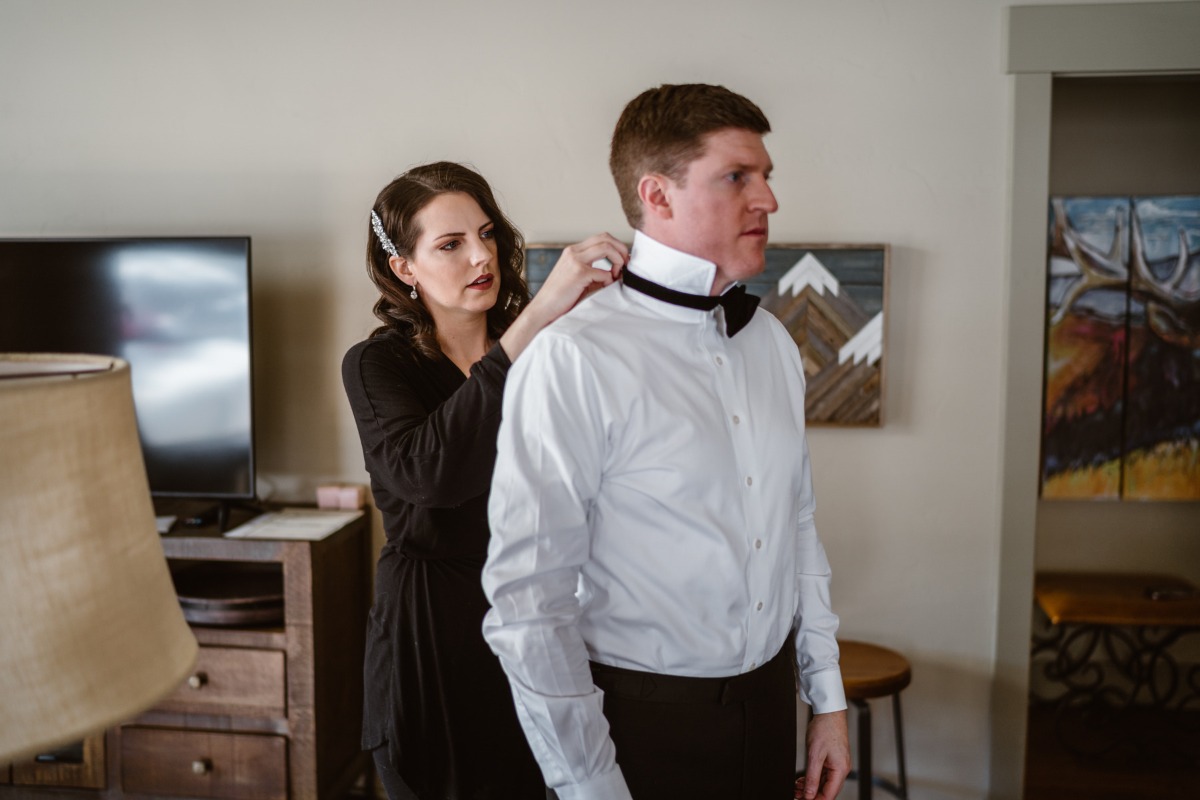 Woman adjusting grooms bow tie before the wedding ceremony