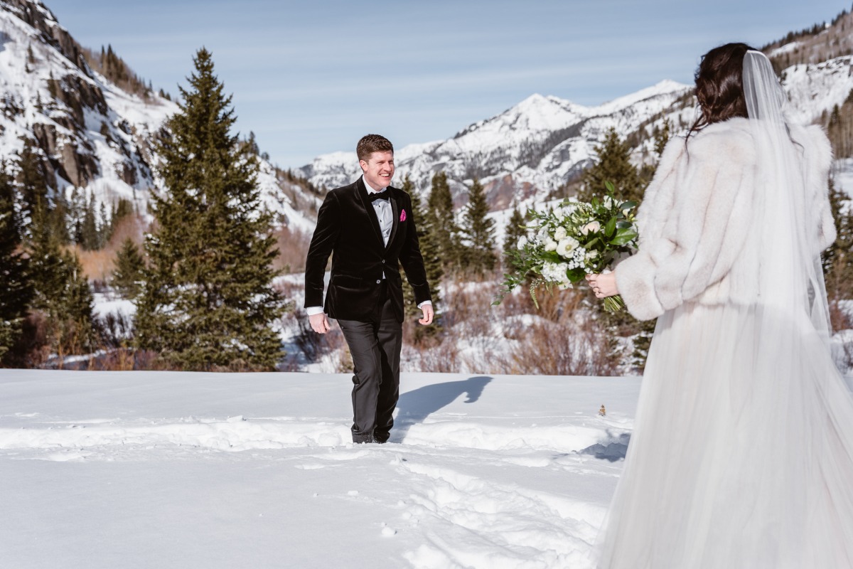 Groom walking to his bride on a snowy mountain wedding day