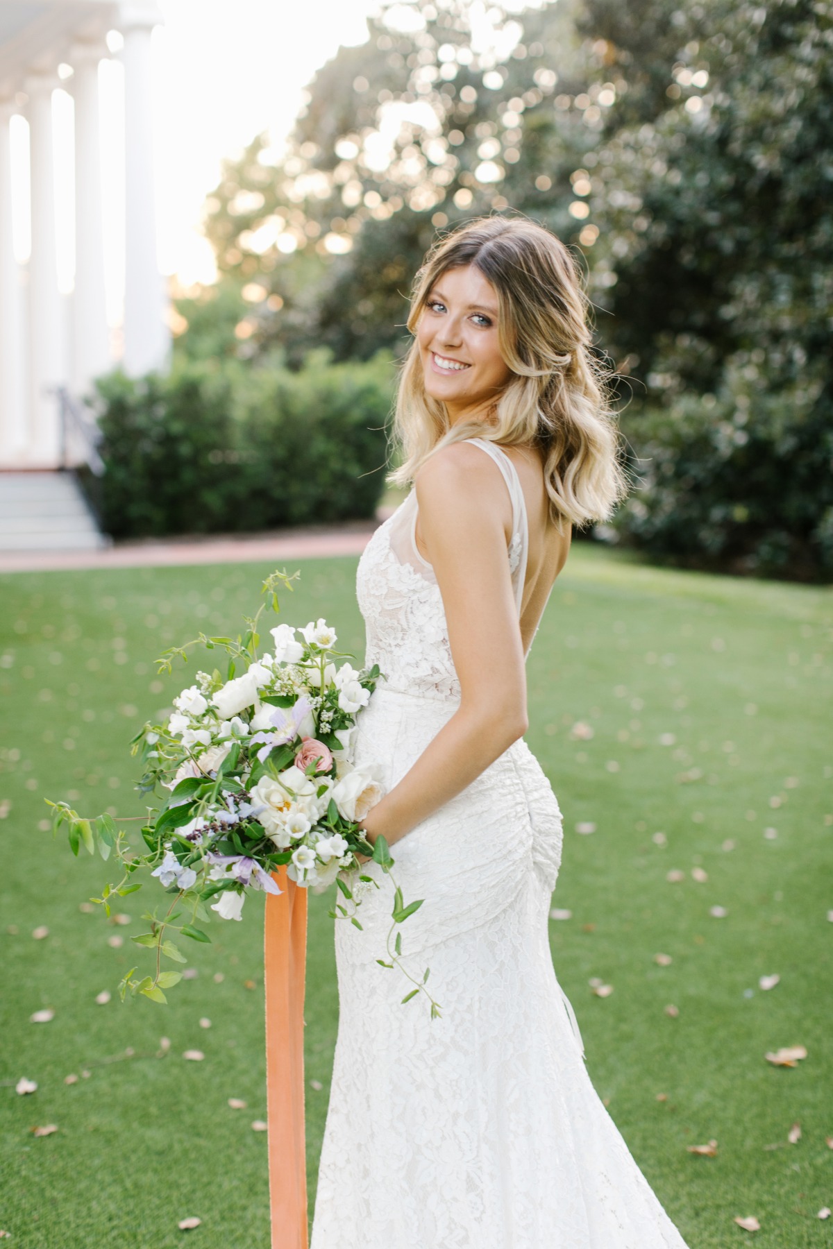 Smiling bride holding flowers wearing a white wedding dress outdoors